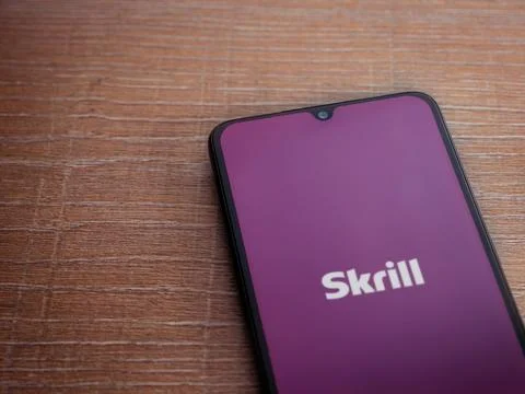 Skrill app launch screen on smartphone on wooden background Stock Photos