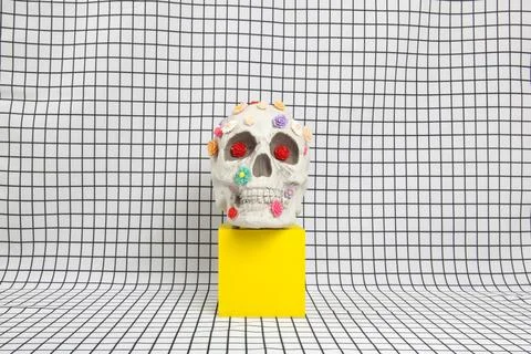 A skull covered with multiple plastic flowers on a white squared tile pattern Stock Photos