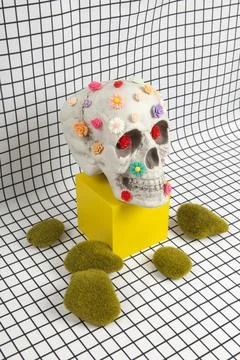 A skull covered with multiple plastic flowers and moss rock Stock Photos