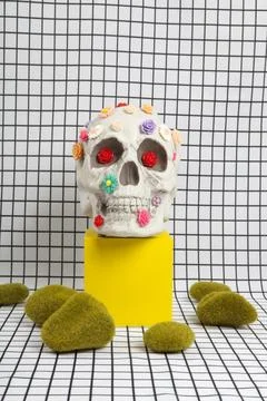 A skull covered with multiple plastic flowers and moss rock Stock Photos
