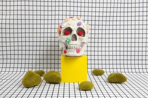 A skull covered with multiple plastic flowers and moss rock Stock Photos