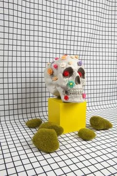 A skull covered with multiple plastic flowers and moss rock Stock Photos