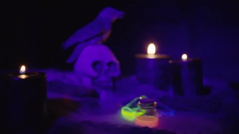 Skull with crow, candles, vials with glowing liquid and smoke. UV and candleligh Видео 117770033