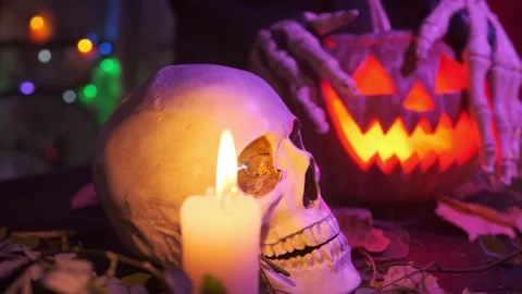 A skull next to Jack Lantern carved from a pumpkin who is strangled by the hands Stock Footage 252130959