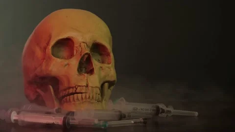 A skull in a red glow stands on a table with syringes 2 Stock Footage 156796069