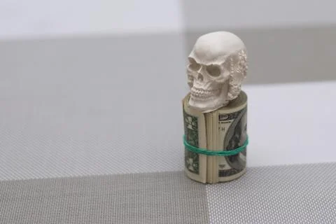 A skull standing on a bundle of money, twisted into a bundle Stock Photos