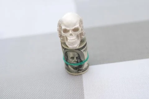 A skull standing on a bundle of money, twisted into a bundle Fotos Stock