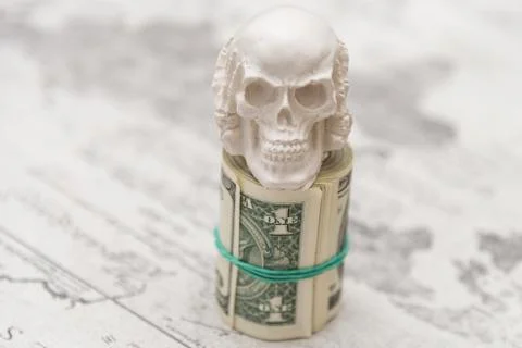 A skull standing on a bundle of money, twisted into a bundle Foto stock