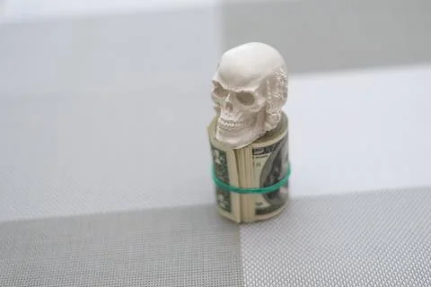 A skull standing on a bundle of money, twisted into a bundle Stock Photos