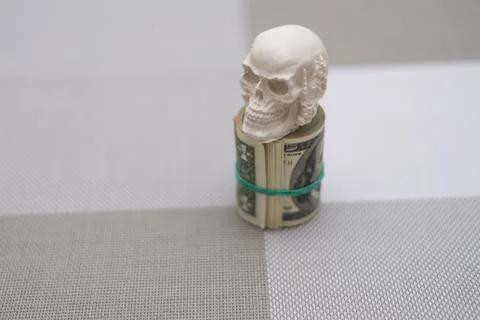 A skull standing on a bundle of money, twisted into a bundle Stock Photos