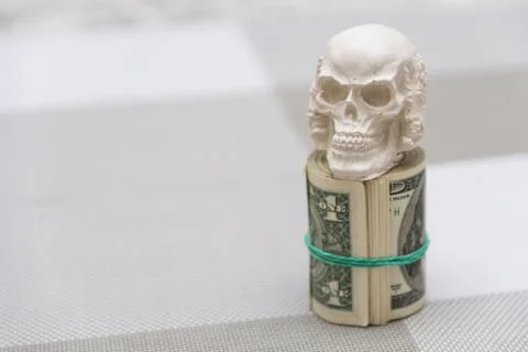 A skull standing on a bundle of money, twisted into a bundle Stock Photos