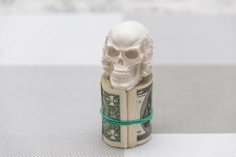 A skull standing on a bundle of money, twisted into a bundle Stock Photos