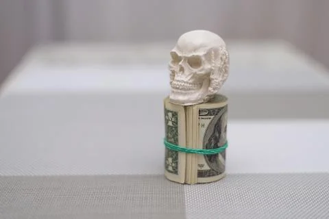 A skull standing on a bundle of money, twisted into a bundle Stock Photos