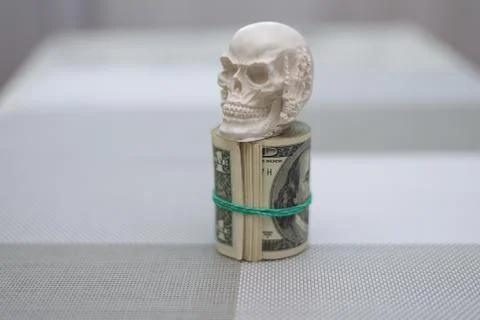 A skull standing on a bundle of money, twisted into a bundle Stock Photos