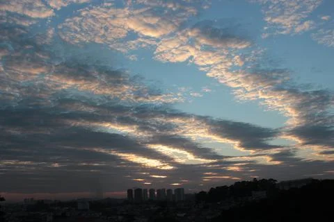 Sky above the city. Multi colored clouds. Background. Buildings shadows. Stock Photos