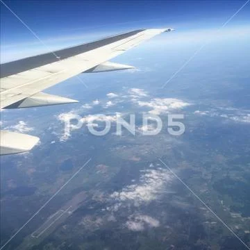 Sky up above the clouds viewed inflight on a passenger airplane. Stock Photos