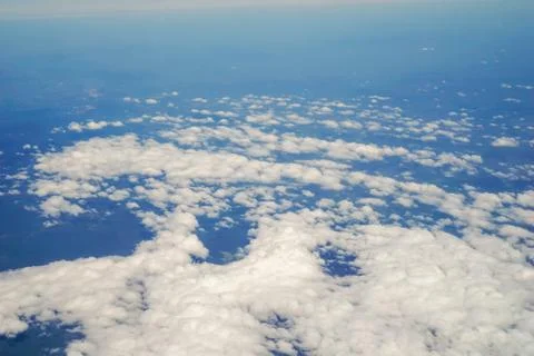 The sky and clouds and the view seen in the window of the plane. Stock Photos