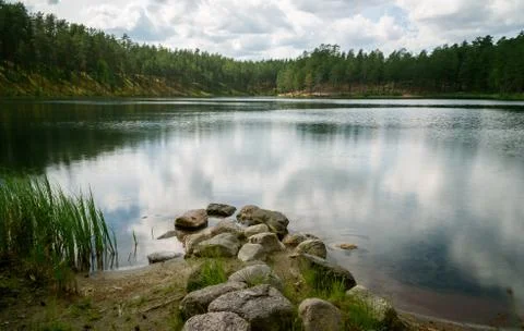Sky and clouds reflecting in forest lake Stock Photos
