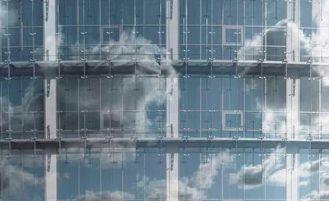 Sky and clouds in reflection of glass window. Modern architecture in detail Stock Photos
