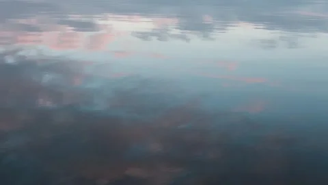 Sky and clouds at sunset are reflected in the calm water Stock Footage 323384513