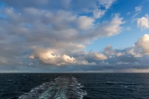Sky and sea surface with wake from vessel at overcast Stock Photos