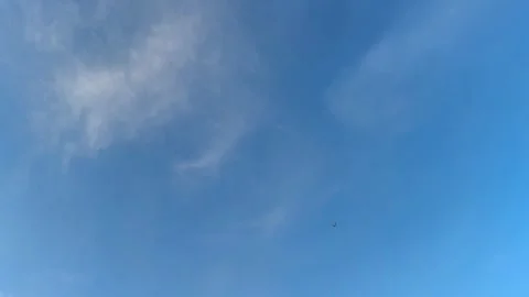 The sky is a beautiful bright blue, with white clouds, airplane creating a Stock Footage 276711964