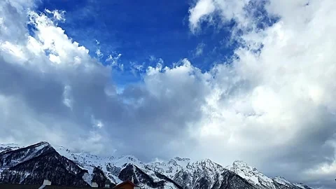 The sky is blue and cloudy with snow on the mountains Stock Footage 276310039