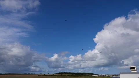 The sky is blue with a few clouds. There are parachutes flying in the sky. Video stock 286090365
