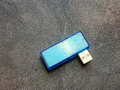 A sky-blue USB flash drive rests upon a dark, textured surface, showing its.. Stock Photos
