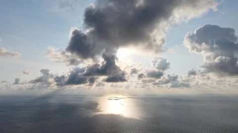 Sky breaks through clouds, casting golden light across calm sea Vídeo Stock 332589160