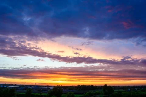 Sky with brigth clouds and setting sun over trees Stock Photos
