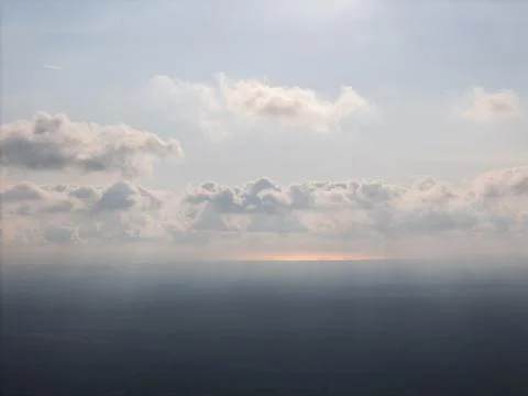 Sky with clouds above distant land during bright day light Stock Photos