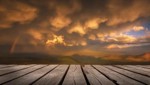 The Sky With Clouds And A Rainbow After The Rain with empty wooden table. Nat Stock Photos