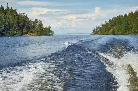 Sky with clouds over the water. a trace of a boat on the water surface, waves Stock Photos