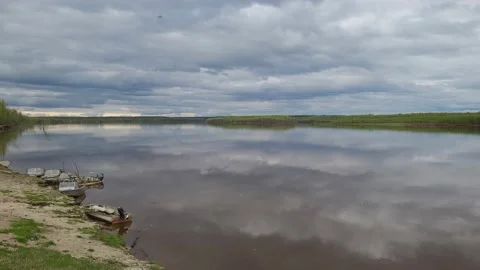 The sky with clouds is reflected in the river. Boats on the coast. Video stock 195215583