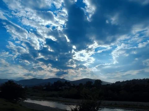 Sky with clouds, sun rays and reflection in the river Stock Photos