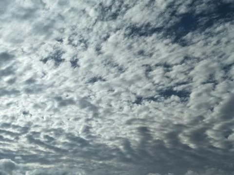 The sky is cloudy with altocumulus clouds and the sun peeking through them. 스톡 사진