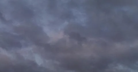 The sky covered with dark clouds with pink reflections of the setting sun Stock Photos