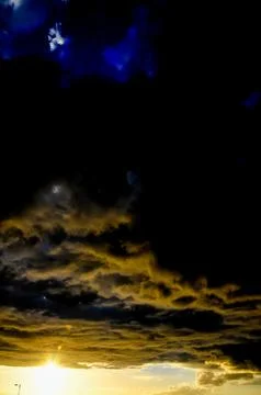 The sky is dark and cloudy with a bright sun in the background 写真素材