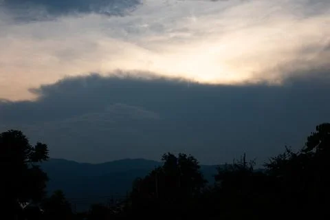 The sky is dark and cloudy, with a few trees in the background Stock Photos
