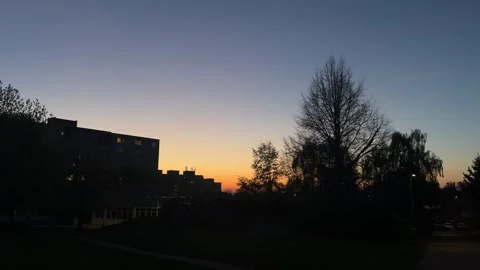 Sky displaying a colorful gradient during an urban sunset, with residential Stock Footage 333512111