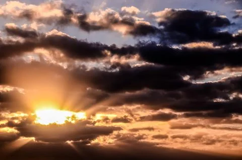 The sky is filled with clouds and the sun is shining through them Stock Photos