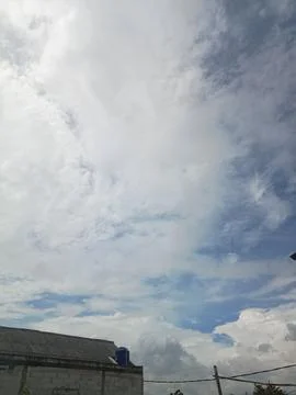 A sky filled with clouds during the day with a white house Foto stock