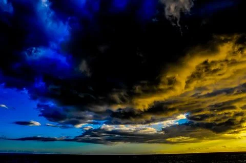 The sky is filled with dark clouds and a few bright blue ones Stock Photos