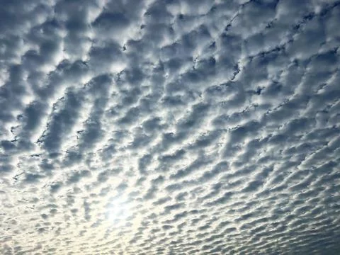 Sky filled with patterned fluffy clouds and sunlight Stock Photos