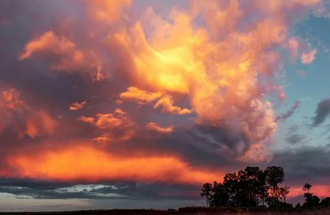 Sky filled with thick clouds illuminated with orange and yellow colors. 스톡 사진