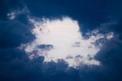 Sky frame surrounded by dark blue storm clouds at sunset. Stock photo of a ro Foto stock