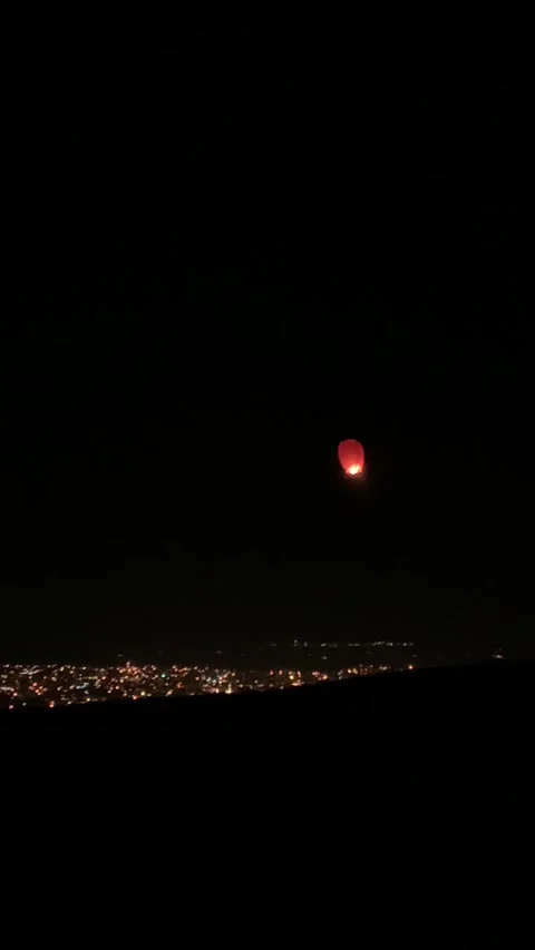 Sky lantern floating in the night sky over a city, Vídeos de archivo 336849453