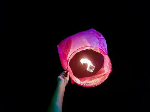 Sky lantern lighting by a pair of hands holding the paper hot air balloon in  Stock Photos