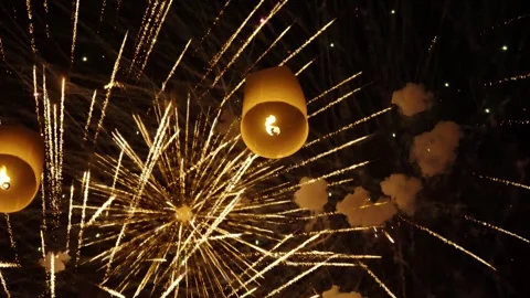 Sky lanterns float upward through a burst of golden fireworks during Yi Peng Stock Footage 308683256